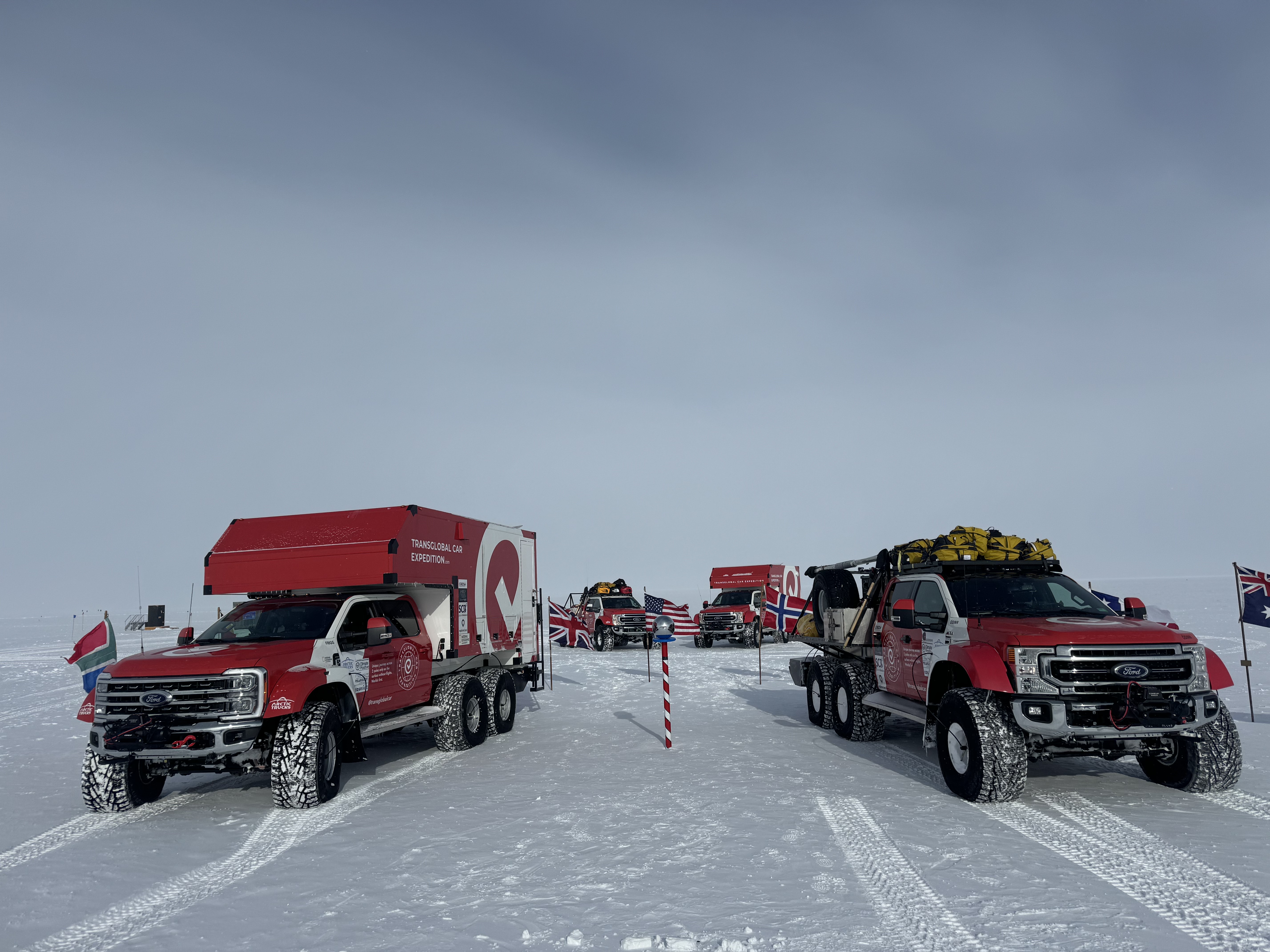 Two modified Ford Super Duty trucks park on either side of the South Pole.